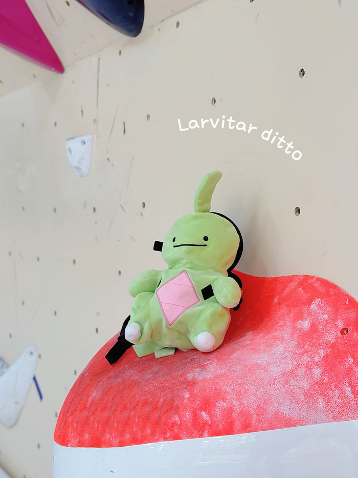 Handmade green and red plush Larvitar rock eater climbing chalk bag with a minimalist mimic face. Cute and unique climbing gift by Fatworm.