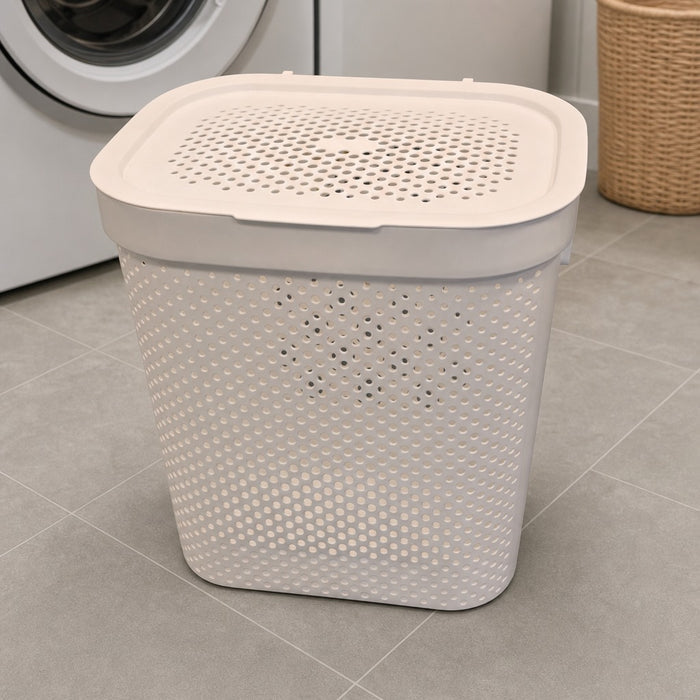 laundry basket with beige lid on a tiled floor next to a washing machine.