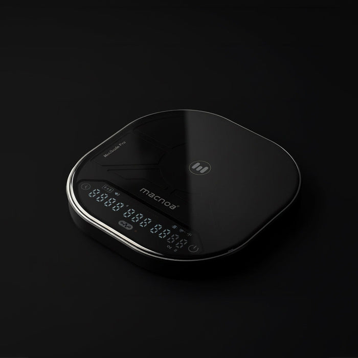 A sleek Macnoa MacScale Pro Smart Coffee Scale with rounded edges, a glossy finish, and a silver metallic trim around the front display panel. The brand name 'macroni' is printed on the front, and the display is illuminated with white digital numbers.