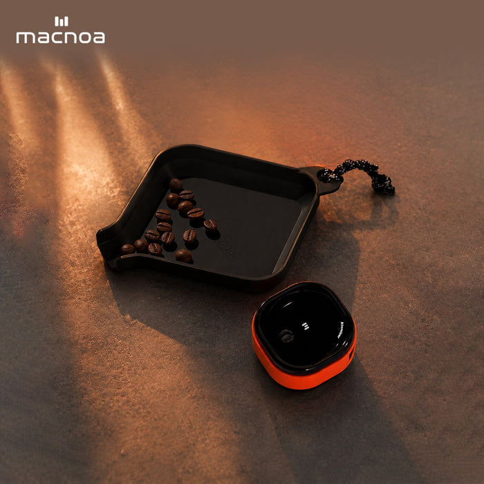 Small black tray with coffee beans and a red and Macnoa MacX mistFlow Electric Coffee Atomizer on a textured surface, featuring the brand 'macnoa'.