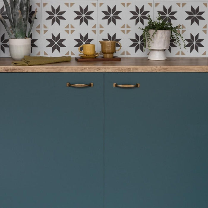 A green matte adhesive vinyl applied to kitchen cabinets with a patterned wall in the background.