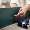 A hand attaching a drawer handle onto a mallard green matte vinyl wrapped drawer.