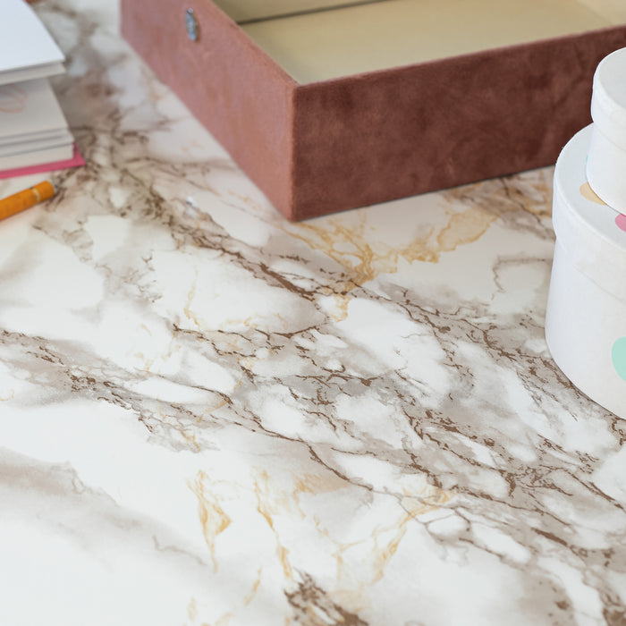 Marble-patterned surface with a book, pencil, and container on a desk.