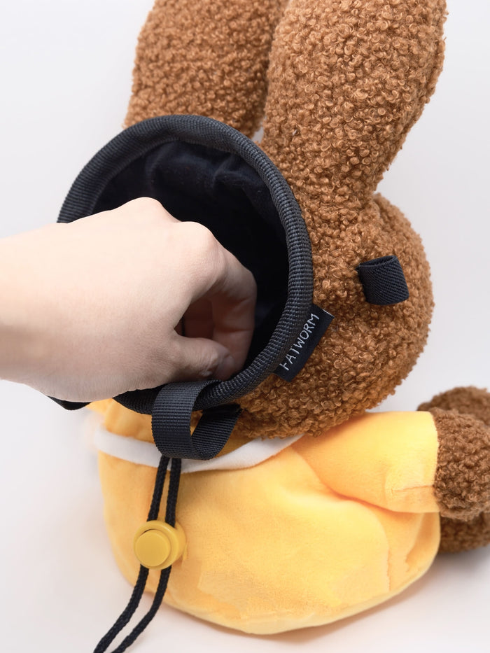 A cute anime plush chalk bag by FATWORM featuring a brown Mocha Bunny wearing a yellow dress. This functional and fluffy bouldering accessory is handmade for bouldering and climbing for rock climbing, offering a long-durable design that makes the perfect climbing gift for a climber.