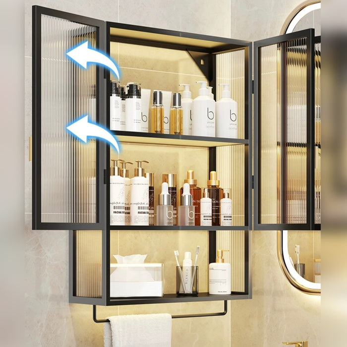Wall-mounted storage organizer with ribbed glass doors, displaying neatly arranged bottles and cosmetics, and an open lower shelf holding folded towels
