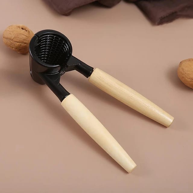 A Nutcracker Tool placed near to a nut on plain surface a plain