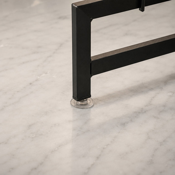 Close-up of a black metal leg of a Over-Sink Dish Drying Rack with a clear circular suction cup base, shown on a white marble surface.