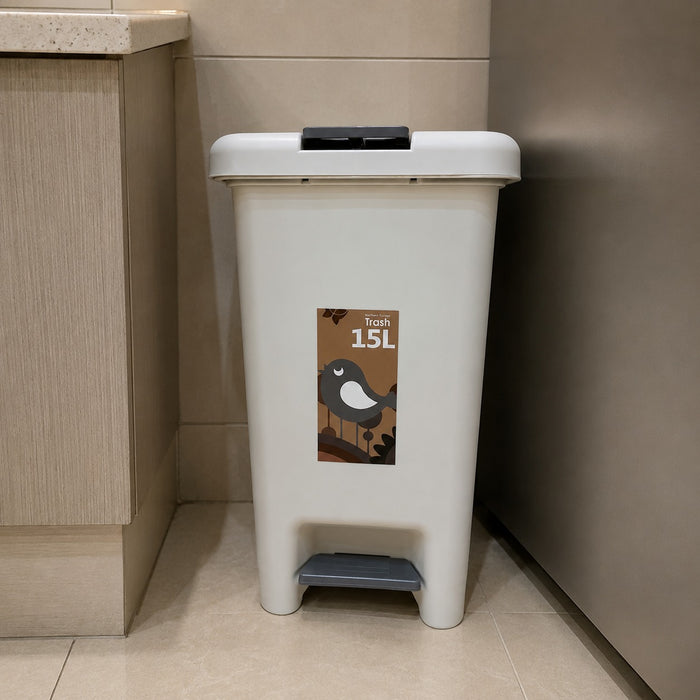 A 15L plastic waste bin with a foot pedal and a black lid, placed in a kitchen corner next to a refrigerator. The bin features a brown label with a cartoon bird and the text 'Towns 15L'.