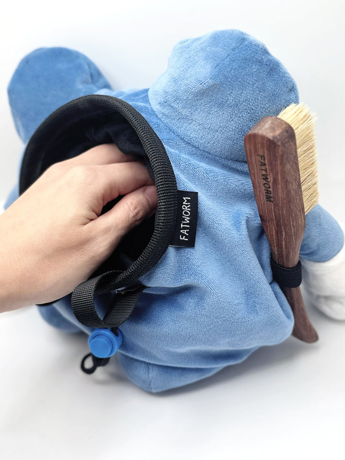 A cute anime plush chalk bag by FATWORM featuring a blue tadpole with a black and white swirl on its belly and white gloves. This functional and fluffy bouldering accessory is handmade for bouldering and climbing for rock climbing, offering a long-durable design that makes the perfect climbing gift for a climber.