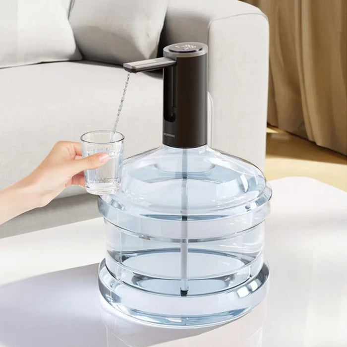 A Porodo foldable electric water pump is mounted on top of a large water bottle, and a person is dispensing water into a small glass.