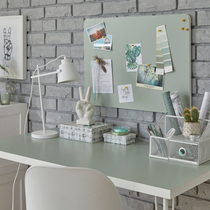 A desk and a pegboard vinyl wrapped with sage green matte adhesive vinyl in a room with office accessories.