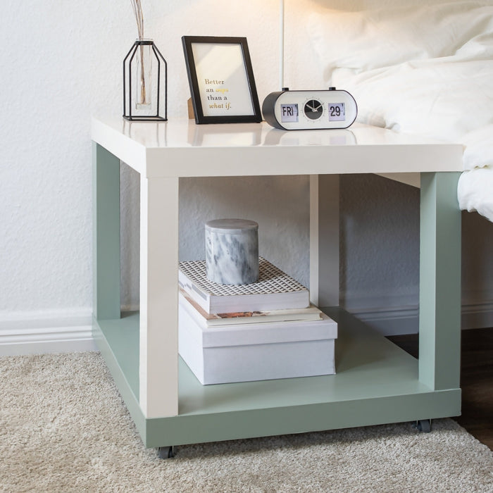 A vinyl wrapped bedside table in sage green and cream with books, a clock and accessories.