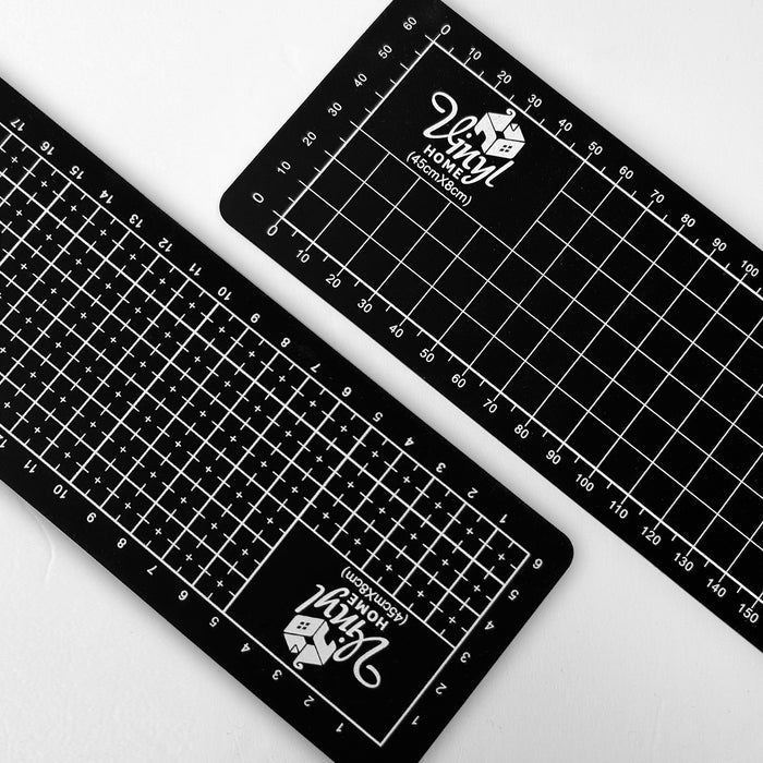 Two black cutting mats with grid lines and measurements on a white background