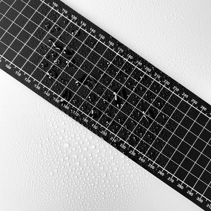 Black grid cutting mat with water drops on a textured white surface