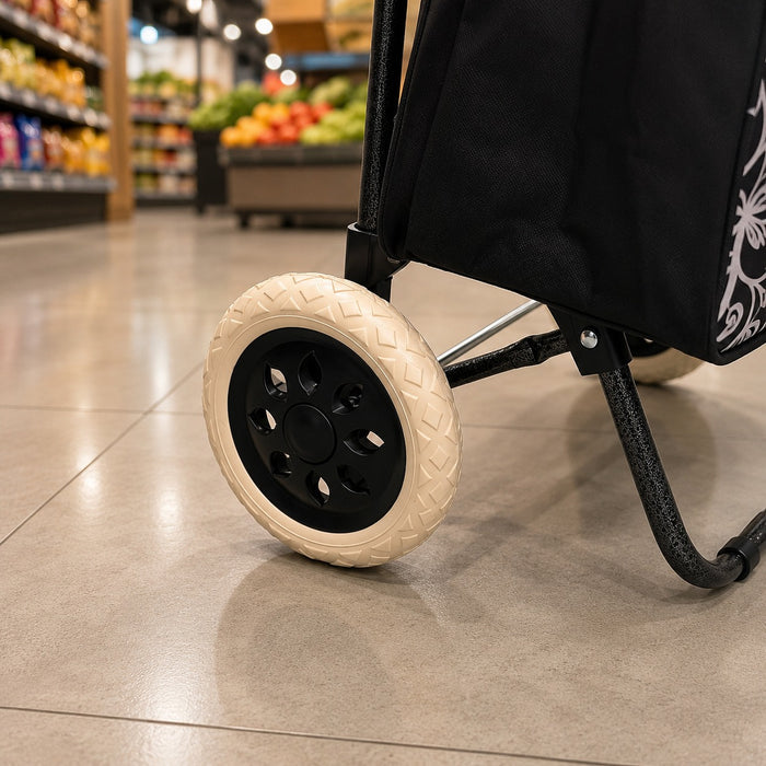 A close-up of a black shopping cart wheel with a cream-colored treaded outer tire, positioned on a polished tile floor inside a grocery store.