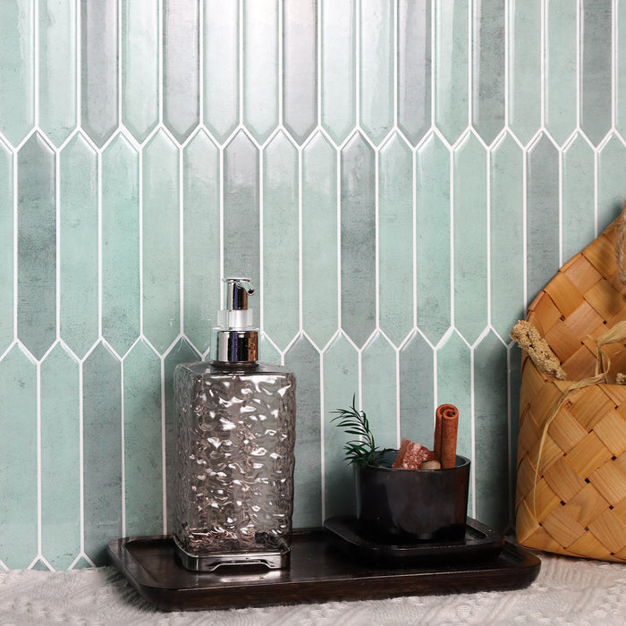 Decorative setup with a textured bottle, plant, and basket against a geometric tile wall.