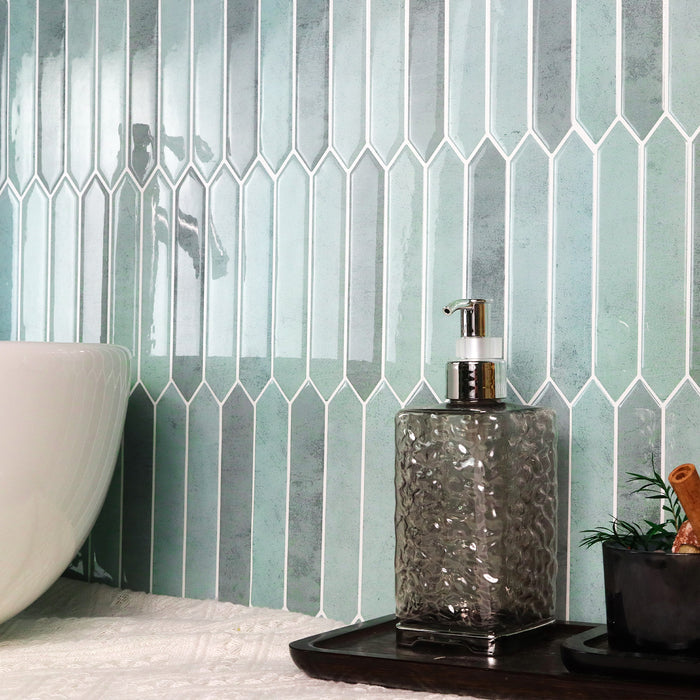 Bathroom setting with a geometric tile pattern on the wall, a soap dispenser, and a plant.
