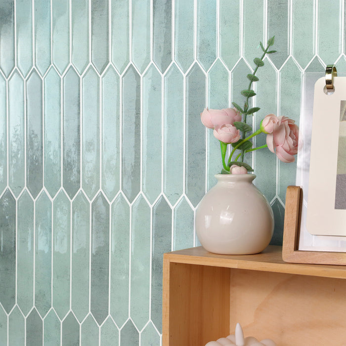 Vase with pink flowers on a wooden shelf against a geometric tile wall.