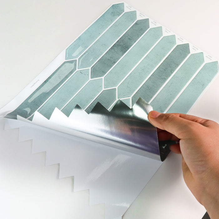 Hand applying a decorative self-adhesive tile sheet with geometric pattern to a surface.