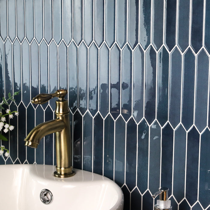 Bathroom sink with gold faucet against a blue tiled wall