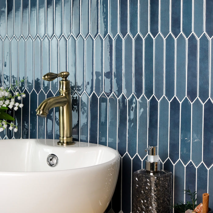 Bathroom setting with a white sink, gold faucet, and blue tiled wall.