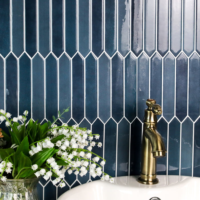Blue tiled wall with a gold faucet and white flowers in the foreground