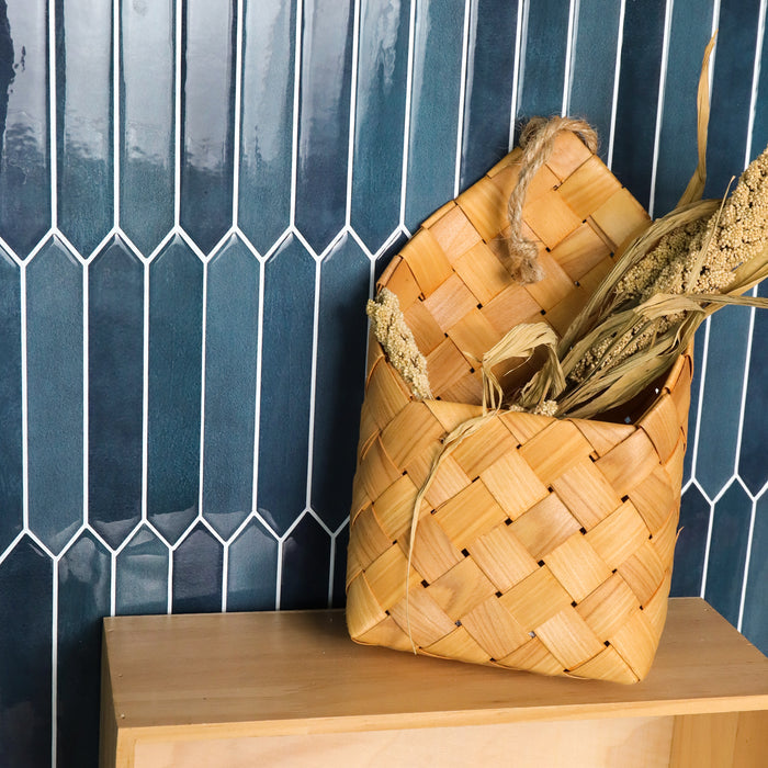 Woven basket with dried plants against a blue tiled wall