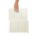 White hexagonal tiles with a hand holding one tile on a white background
