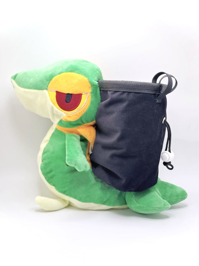 A cute, handmade plush climbing chalk bag designed to look like the Snivy, featuring a sleek green and cream body with yellow leaf-like accents and large, confident eyes. Designed with high functionality by a climber, it includes a wide black rim opening at the top for easy chalk access. A great climbing gift for trainers who want to catch them all.
