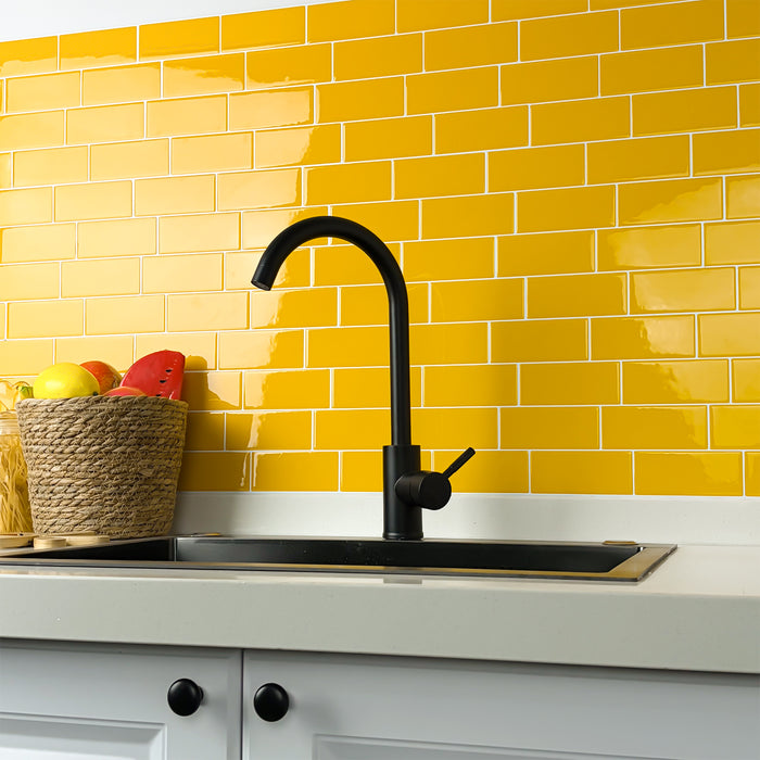 Kitchen sink with black faucet against a yellow tiled wall