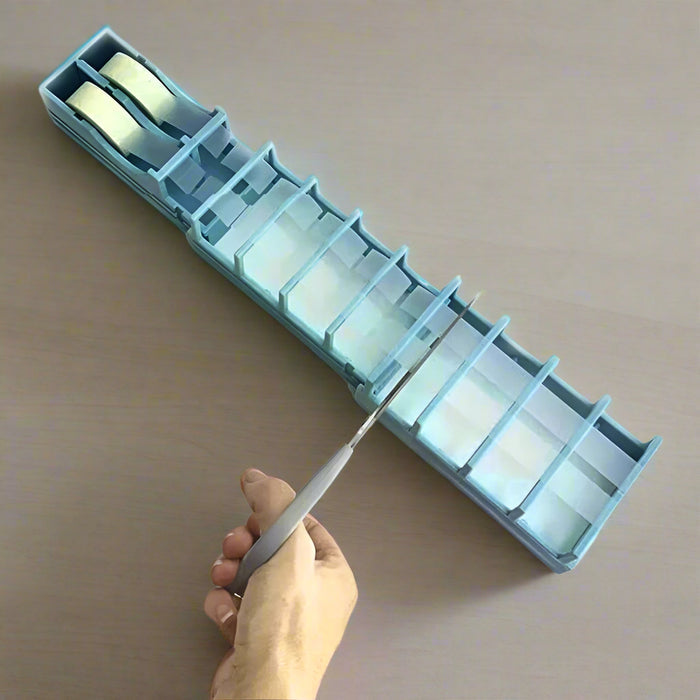 A person using scissors to cut tape strips from a blue tape dispenser