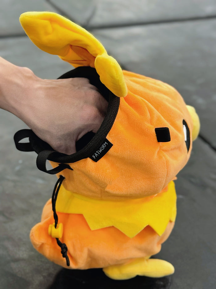 Handmade orange plush Torchic fire chick climbing chalk bag for bouldering. Features yellow feather tufts and a cute bird silhouette. High-quality plush bouldering gift with a 12cm reinforced rim, secure drawstring, and deep black fleece lining for rock climbing.