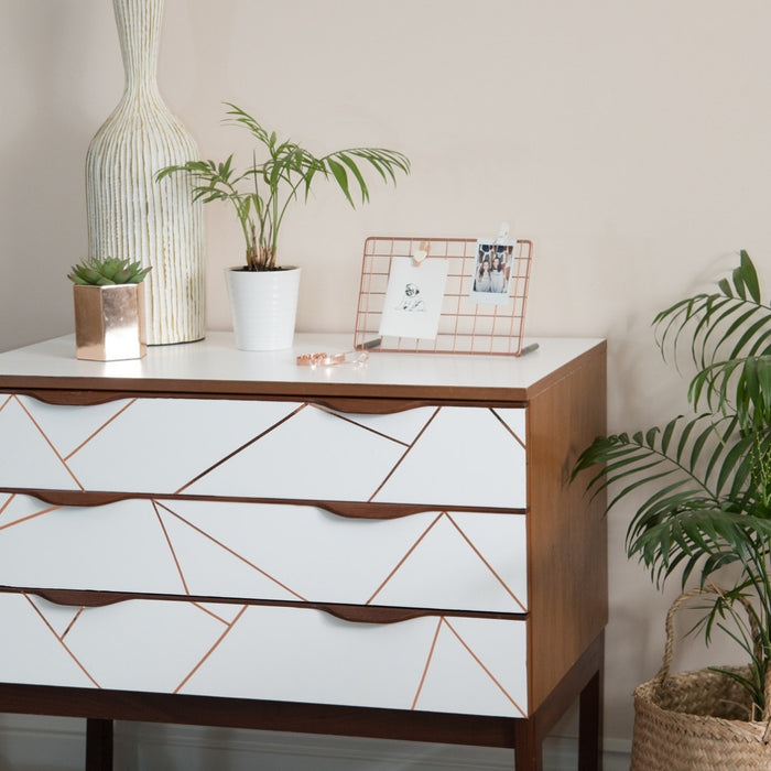 A white matte adhesive vinyl with a geometric pattern applied to a piece of furniture, in a room setting with plants and decorative items.